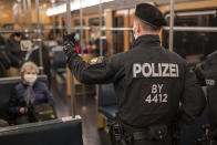 Police officers and an employee of VAG (Verkehrs-Aktiengesellschaft Nuernberg) in a subway train to control the mask requirement, to avoid the spread of the coronavirus, on the public transport service in Nuernberg, Germany, Friday, Oct. 23, 2020. (Daniel Karmann/dpa via AP)