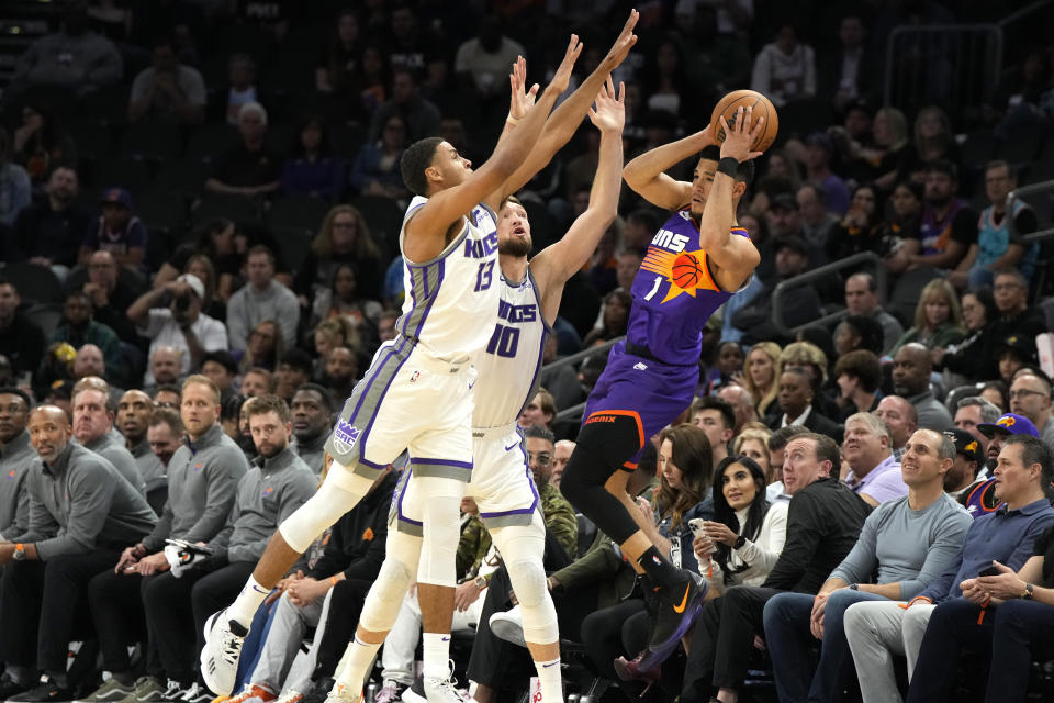 Sacramento Kings forward Keegan Murray (13) and forward Domantas Sabonis pressure Phoenix Suns guard Devin Booker (1) during the first half of an NBA basketball game, Saturday, March 11, 2023, in Phoenix. (AP Photo/Rick Scuteri)