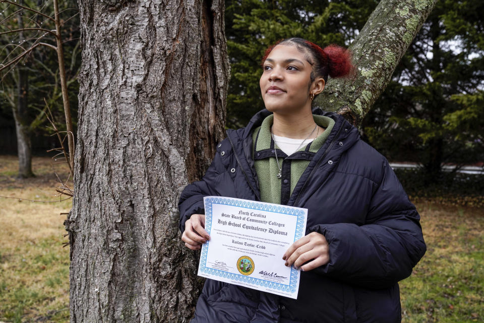 Kailani Taylor-Cribb holds her GED diploma outside her home in Asheville, N.C., on Tuesday, Jan. 31, 2023. She is among hundreds of thousands of students around the country who vanished from public school rolls during the pandemic and didn’t resume studies elsewhere. (AP Photo/Kathy Kmonicek)