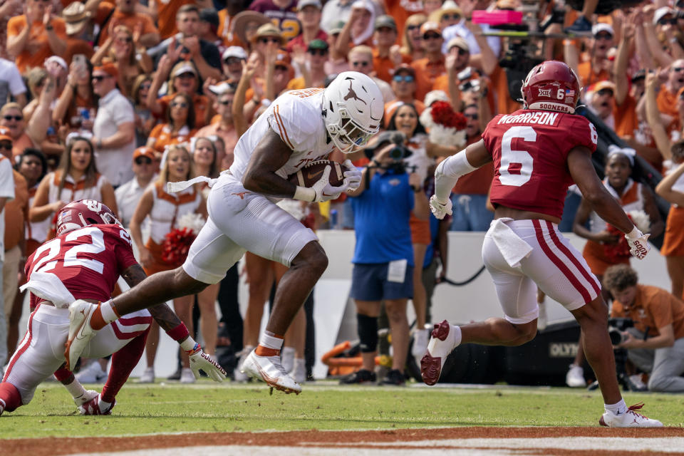 Texas tight end Ja'Tavion Sanders (0) runs into the end zone on a touchdown reception in front of Oklahoma defensive backs Trey Morrison (6) and C.J. Coldon (22) during the first half of an NCAA college football game at the Cotton Bowl, Saturday, Oct. 8, 2022, in Dallas. (AP Photo/Jeffrey McWhorter)