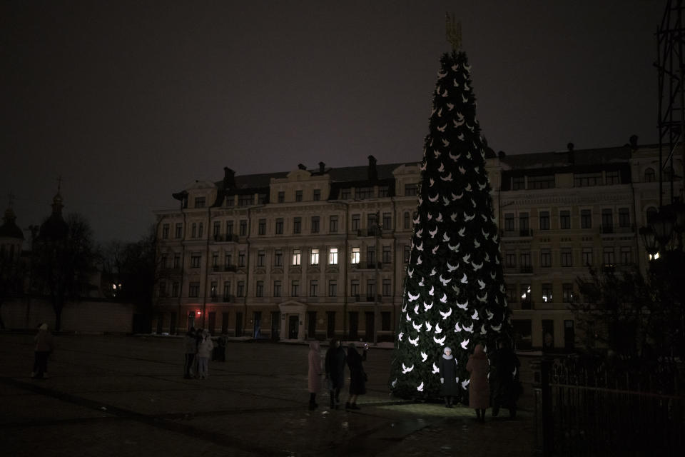 Ukrainians take photos of a newly built Christmas tree as partial power outages continue in Kyiv, Ukraine, Saturday, Dec. 17, 2022. (AP Photo/Felipe Dana)
