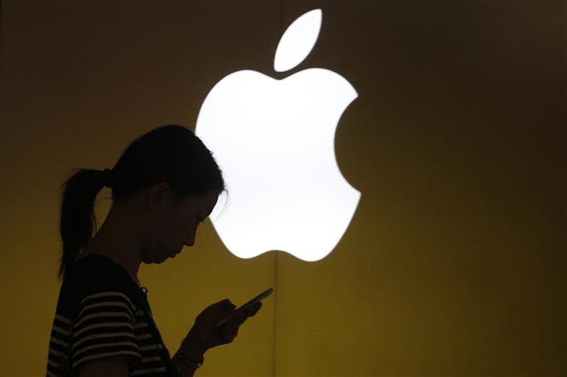 A woman looks at the screen of her mobile phone in front of an Apple logo outside its store in downtown Shanghai September 10, 2013. REUTERS/Aly Song