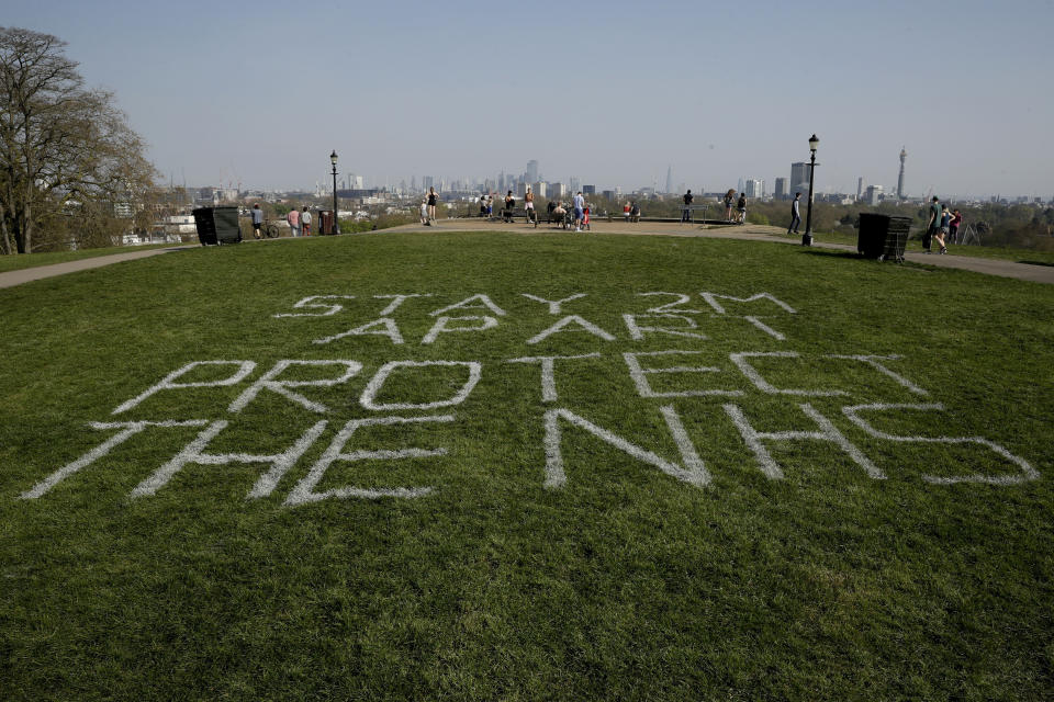 Recently painted words saying "Stay 2 M apart protect the NHS" displayed to try and stop the spread of coronavirus through encouraging people to observe two-meters social distancing, on the grass of Primrose Hill in London, Friday, April 10, 2020. In a statement Thursday, a spokesman at 10 Downing Street said British Prime Minister Johnson "has been moved this evening from intensive care back to the ward, where he will receive close monitoring during the early phase of his recovery." The new coronavirus causes mild or moderate symptoms for most people, but for some, especially older adults and people with existing health problems, it can cause more severe illness or death. (AP Photo/Matt Dunham)