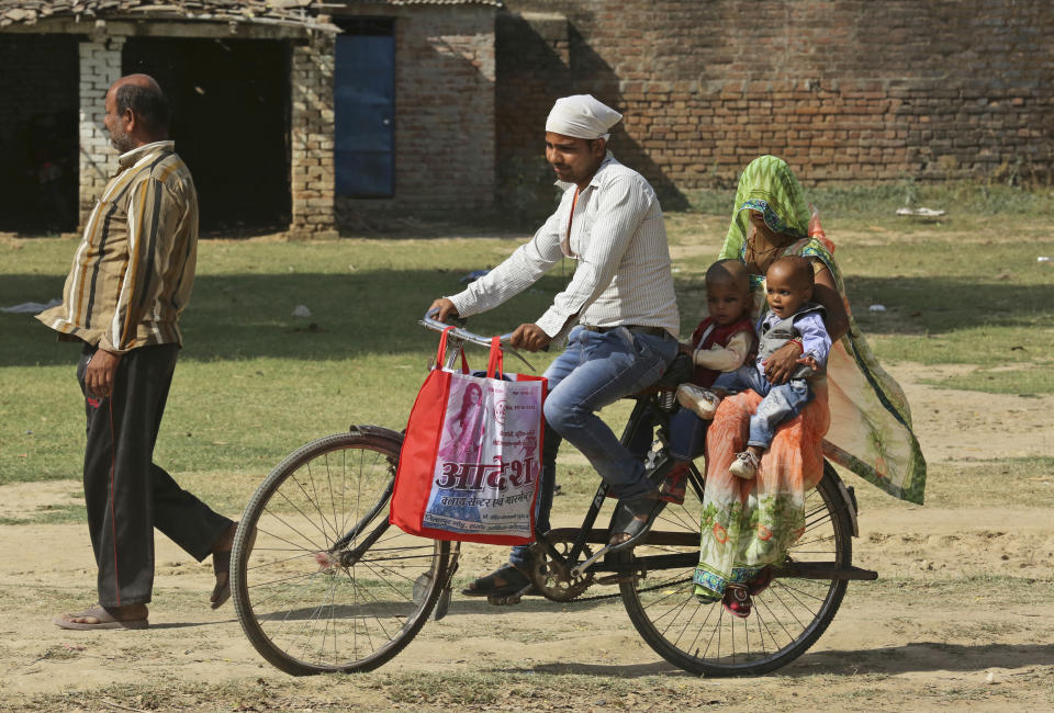 An Indian couple arrives on a cycle with their children to cast their votes in Chayal village, in Kausambi district of Uttar Pradesh state, India, Monday, May 6, 2019. Voting began amid scorching summer temperatures and tight security in Uttar Pradesh in northern India, where more than 25 million people are registered to cast ballots for 14 members of India's Parliament. (AP Photo/Rajesh Kumar Singh)