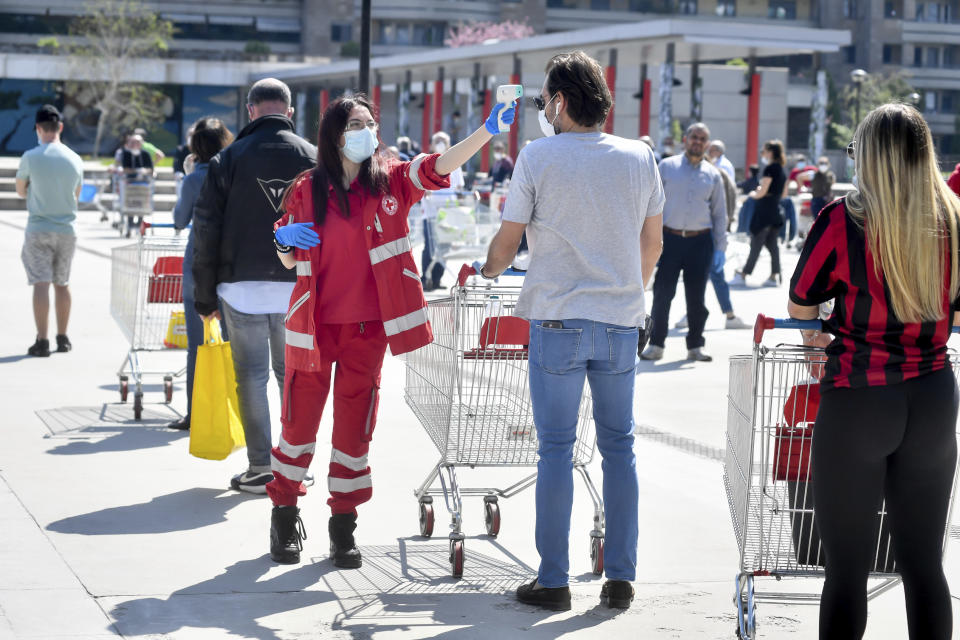 A shopper has his temperature scanned as he stands in a long line waiting to enter at the Esselunga supermarket in San Donato, in the outskirts of Milan, Italy, Saturday, April 11, the day before Easter, when most Italian will try to mitigate the boredom of the coronavirus lockdown with the traditional lunch. The new coronavirus causes mild or moderate symptoms for most people, but for some, especially older adults and people with existing health problems, it can cause more severe illness or death.(Claudio Furlan/LaPresse via AP)