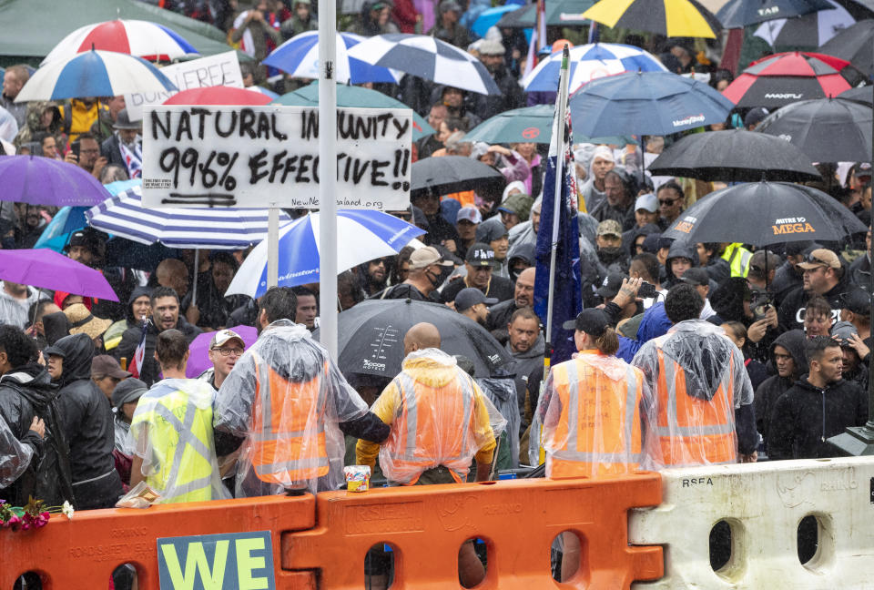 Protesters gather in wet conditions as they voice their opposition to coronavirus vaccine mandates at Parliament in Wellington, New Zealand, Saturday, Feb. 12, 2022. The protest began when a convoy of trucks and cars drove to Parliament from around the nation, inspired by protests in Canada. (Mark Mitchell/NZME via AP)
