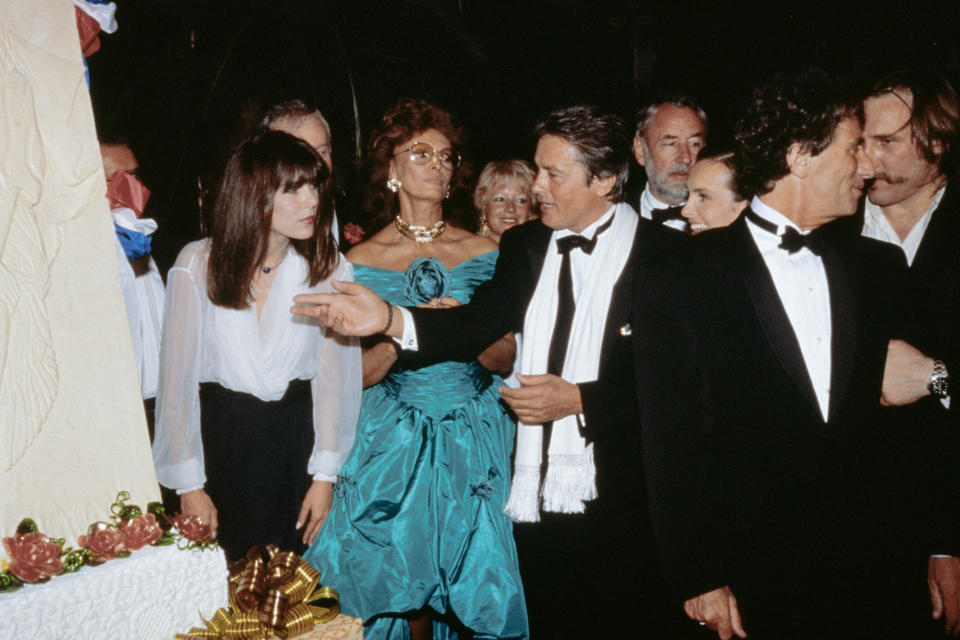 <p>(From L to R), Princess Caroline of Monaco, Italian actress Sophia Loren, French actor Alain Delon, French actor Philippe Noiret, French actress Carole Bouquet, French actor Gerard Depardieu and French Minister of Culture Jack Lang surround a big cake which represents The French Revolution bicentenary at the 42th edition of the Cannes Film Festival in Cannes, southern France on May 11, 1989. (Photo by AFP) (Photo by -/AFP via Getty Images)</p>
