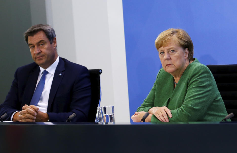 Bavarian State Prime Minister Markus Soeder and German Chancellor Angela Merkel attend a news conference following a meeting with leaders of the 16 federal states to discuss the country's response following the spread of the coronavirus, at the Chancellery in Berlin, Thursday, Aug. 27, 2020. In an effort to harmonize different coronavirus measures across the country, Germany will implement a nationwide fine for people not wearing face masks and also ban mass events until the end of the year, Chancellor Angela Merkel said Thursday. (Michele Tantussi/Pool Photo via AP)