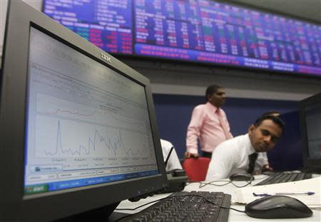 A broker is pictured near a computer screen showing movements in the stock market (top graph) since the morning opening at the Colombo Stock Exchange February 6, 2014. Asian shares took a tentative step forward from five-month lows on Thursday, with investors hoping the European Central Bank (ECB) and upcoming U.S. jobs data can calm nerves strained by the emerging market selloff. REUTERS/Dinuka Liyanawatte
