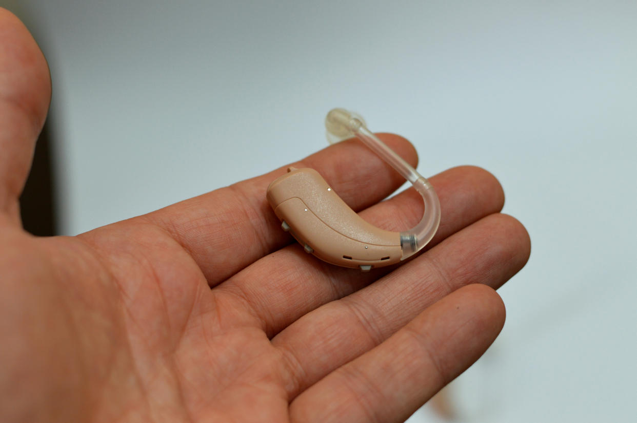 A hand holding hearing aid device.