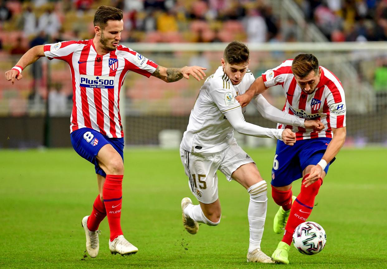 Real Madrid's Uruguayan midfielder Federico Valverde (C) is marked by Atletico Madrid's Spanish midfielder Saul Niguez (L) and Atletico Madrid's Mexican midfielder Hector Herrera during the Spanish Super Cup final between Real Madrid and Atletico Madrid on January 12, 2020, at the King Abdullah Sports City in the Saudi Arabian port city of Jeddah. (Photo by Giuseppe CACACE / AFP) (Photo by GIUSEPPE CACACE/AFP via Getty Images)