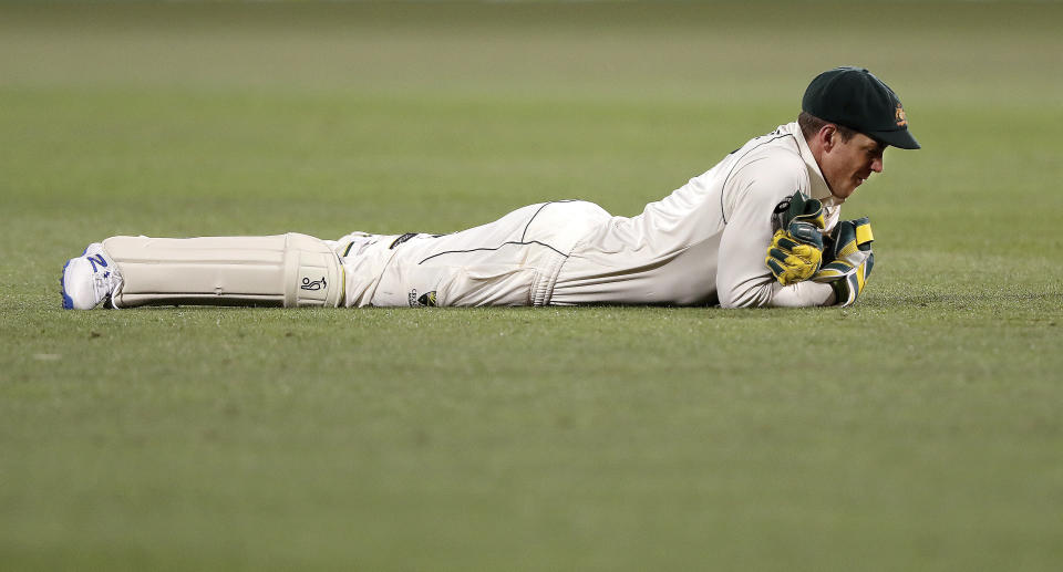 Australia's Tim Paine lays on the ground after dropping a chance to catch out India's Mayank Agarwal on the second day of their cricket test match at the Adelaide Oval in Adelaide, Australia, Friday, Dec. 18, 2020. (AP Photo/James Elsby)