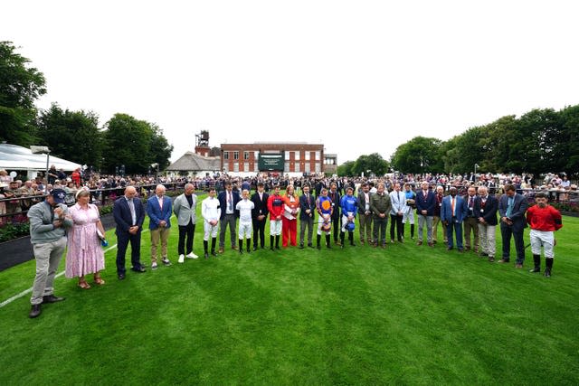 Jockeys stand in a half circle in silence at Newmarket 