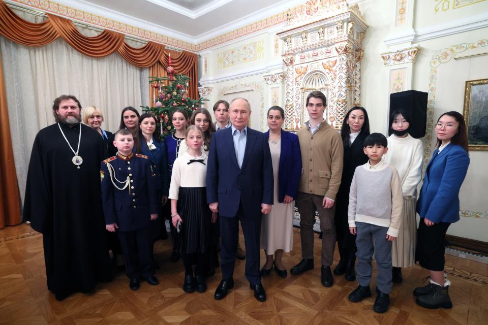 Russian President Vladimir Putin, center, and Russian Orthodox Archbishop of Odintsovo and Krasnogorsk Foma (Nikolay Mosolov), left, pose for a photo with the families of military personnel who died during the special military operation in Ukraine at the Novo-Ogaryovo state residence outside Moscow, Russia, on Saturday, Jan. 6, 2024. (Gavriil Grigorov, Sputnik, Kremlin Pool Photo via AP)