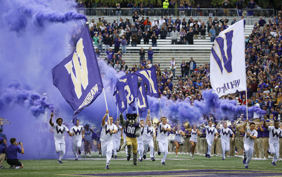 FILE - Washington cheerleaders and Harry, the Husky mascot, set off smoke effects as they lead the team out of the tunnel at Husky Stadium for Washington's home opener, an NCAA college football game against Montana, Saturday, Sept. 9, 2017, in Seattle. Dealing a crushing combination to the Pac-12 on Friday, Aug. 4, 2023, the Big Ten announced Oregon and Washington would be joining the conference next August, and the Big 12 completed its raid of the beleaguered league by adding Arizona, Arizona State and Utah. (AP Photo/Ted S. Warren, File)