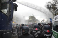 FILE - Police uses water canons to clear a blocked a road between the Brandenburg Gate and the Reichstag building, home of the German federal parliament, as people attend a protest rally in front of the Brandenburg Gate in Berlin, Germany, Nov. 18, 2020 against the coronavirus restrictions in Germany. Police in Berlin have requested thousands of reinforcements from other parts of Germany to cope with planned protests by people opposed to coronavirus restrictions. Germany is set to mark 100,000 deaths from COVID-19 this week, passing a somber milestone that several of its neighbors crossed months ago but which some in Western Europe's most populous nation had hoped to avoid.(AP Photo/Michael Sohn, File)