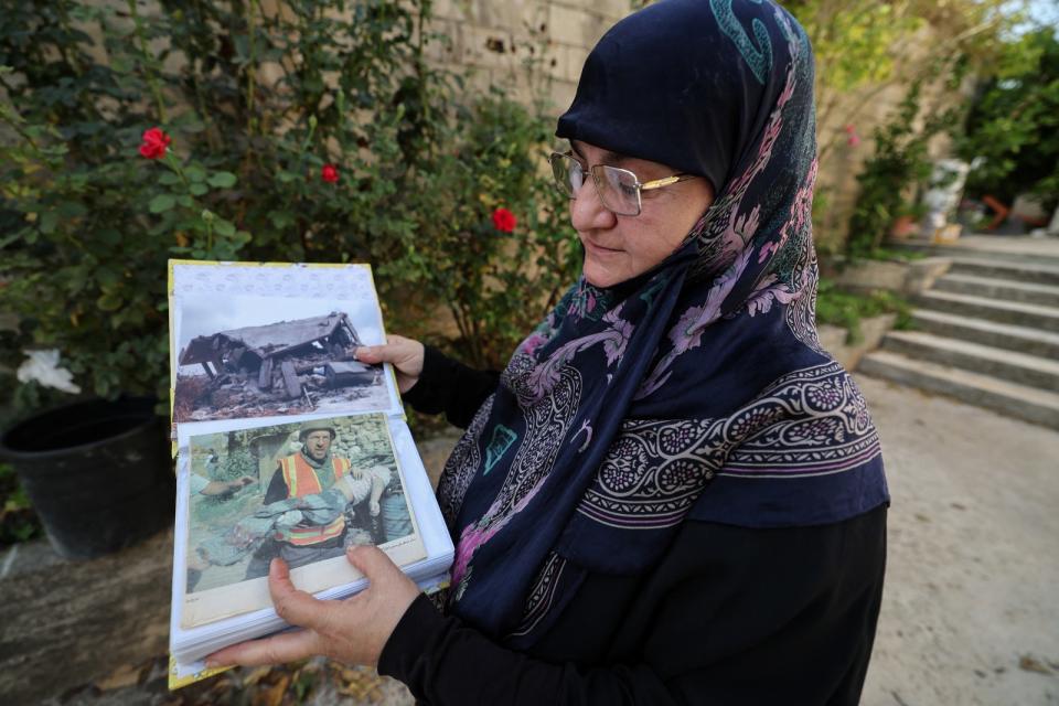 2023年10月24日，黎巴嫩南部邊境卡納村（Qana），57歲的尤塞芙（Rabab Youssef）拿著2006年以色列空襲的照片，其中一張是救難人員抱著她女兒的屍體。路透社