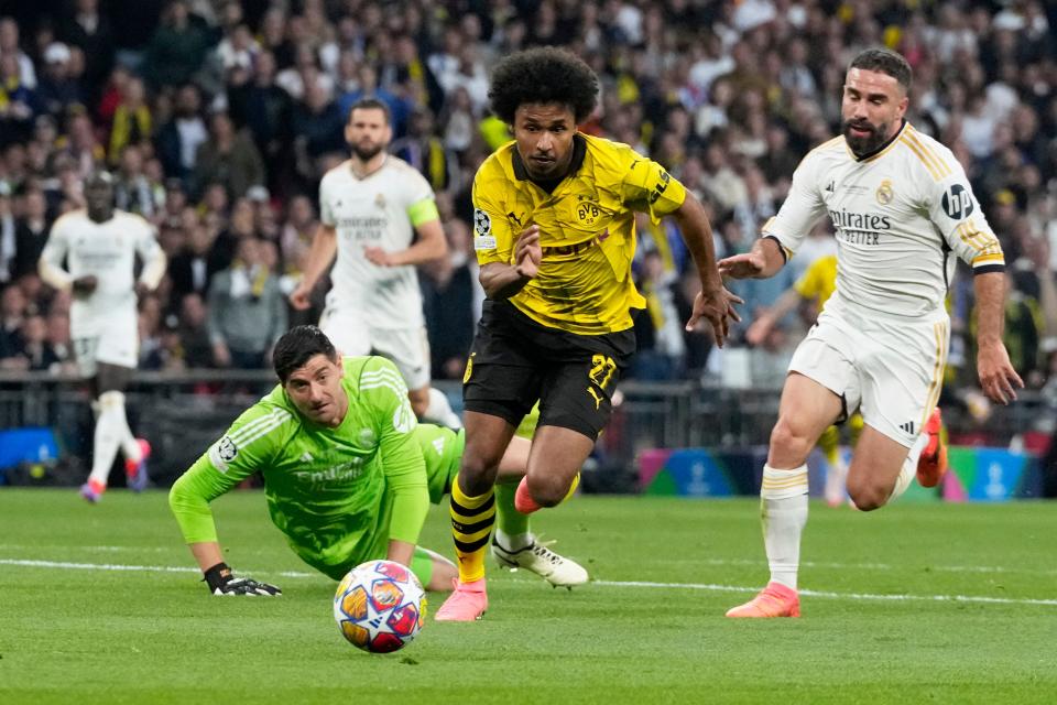 Dortmund's Karim Adeyemi, center, gets past Real Madrid's goalkeeper Thibaut Courtois, on the ground (AP)