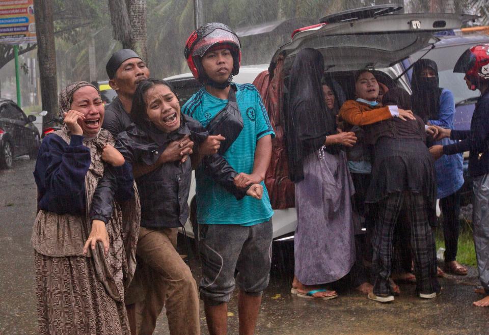 A family after the body of a relative is retrieved from the ruin of a building at an area affected by an earthquake in Mamuju, West Sulawesi, Indonesia, Friday.AP