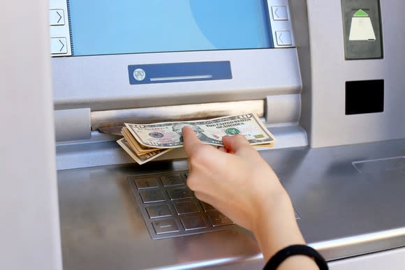 A woman taking money out of a cash machine.