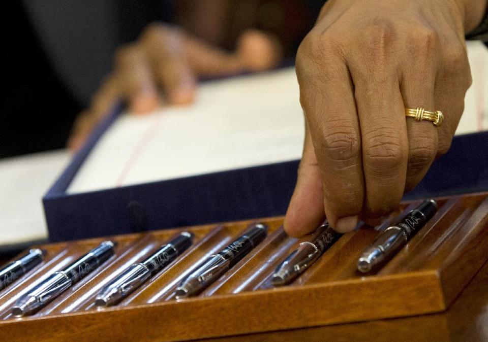 President Barack Obama reaches for a pen as he signs the Honoring America's Veterans and Caring for Camp Lejeune Families Act of 2012, Monday, Aug. 6, 2012, in the Oval Office at the White House in Washington. (AP Photo/Haraz N. Ghanbari)
