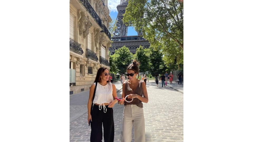 two women walking in front of eiffel tower