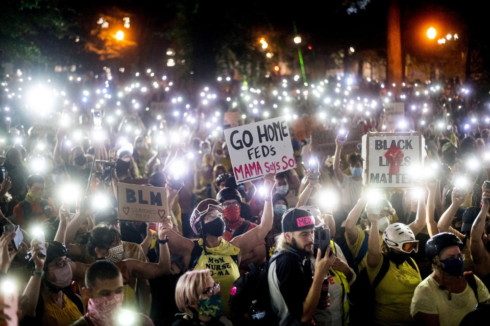 Hundreds of Black Lives Matter protesters hold their phones aloft on Monday, July 20, 2020, in Portland, Ore. Federal officers’ actions at protests in Oregon’s largest city, hailed by President Donald Trump but done without local consent, are raising the prospect of a constitutional crisis — one that could escalate as weeks of demonstrations find renewed focus in clashes with camouflaged, unidentified agents outside Portland’s U.S. courthouse. (AP Photo/Noah Berger)
