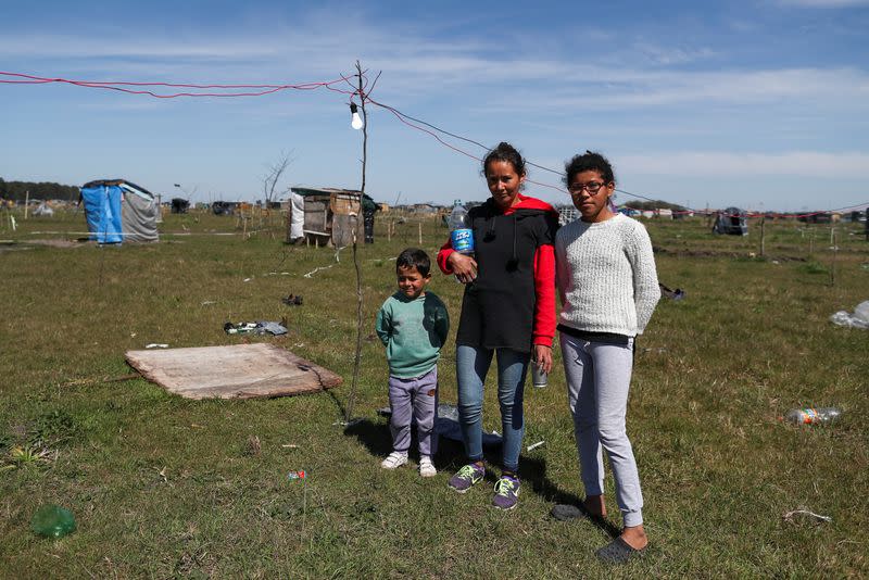 Sandra Verdun, de 29 años, posa para una foto con su hija Erica Verdun, de 11, y su sobrino, en una porción de tierra que ocupó en la localidad de Guernica, en Argentina