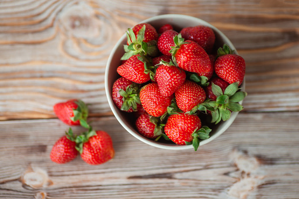 Ripe strawberries in a bowl on a wooden table. Close-up.