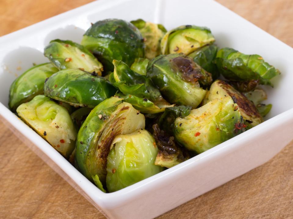 Brussel sprouts in a white bowl on a light wood table