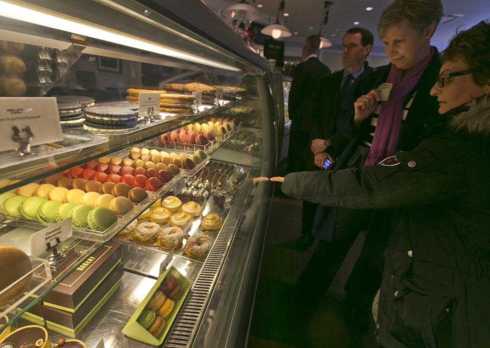 This Dec. 5, 2013 photo shows patrons of Bouchon Bakery, in New York's Rockefeller Center, looking at macarons in the display case. Rockefeller Center is crowded at Christmastime thanks to the famous tree, the skating rink and the show at Radio City Music Hall, but visitors can choose from a variety of places to eat in the area, from ethnic food and street carts to sit-down dining. (AP Photo/Richard Drew)