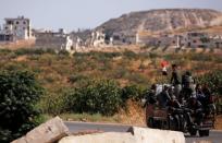 Syrian army soldiers ride at a back of a truck in the town of Morek