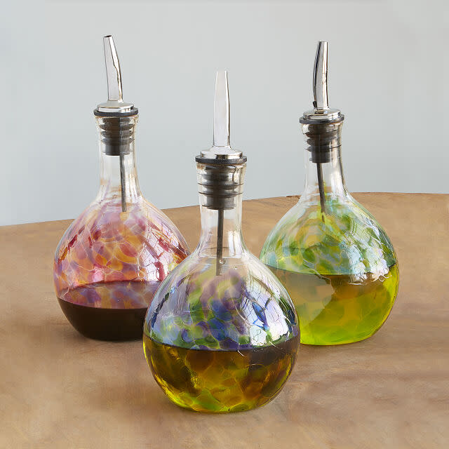 Three Handblown Glass Olive Oil Pourers filled with olive oil.