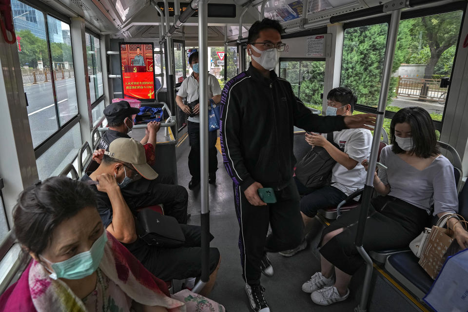 Commuters wearing face masks to help curb the spread of the coronavirus ride on a bus with a tv screen showing Chinese President Xi Jinping speaking during an event to commemorate the 100th anniversary of China's Communist Party at Tiananmen Square in Beijing, Thursday, July 1, 2021. China's ruling Communist Party is marking the 100th anniversary of its founding with speeches and grand displays intended to showcase economic progress and social stability to justify its iron grip on political power. (AP Photo/Andy Wong)