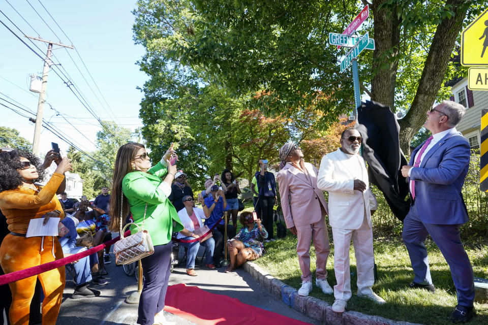 Englewood Mayor Michael Wildes, right, unveils a street sign in honor of the Isley brothers as Ron Isley, center, and Ernie Isley look on during a street renaming ceremony, Thursday, June 24, 2021, in Englewood , N.J. Two New Jersey towns have renamed streets in honor of the Isley Brothers, the legendary R&B group that behind songs such as, "Shout," "Twist and Shout" and "It's Your Thing." Ron Isley and Ernie Isley attended separate ceremonies Thursday in Teaneck and Englewood, neighboring towns outside New York City where they lived during the band's heyday in the 1960s. (AP Photo/Mary Altaffer)