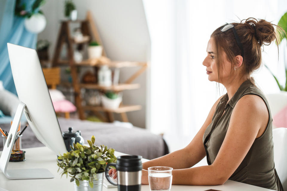 Side view of a woman using computer at office desk.