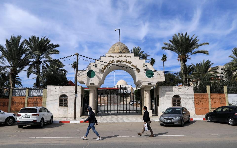 Palestinians walk past the entrance of the Legislative Council building in Gaza City, on 17 January, 2021. The UN has called on Israel to swiftly provide vaccines to Palestinians living in occupied territories. (AFP via Getty Images)