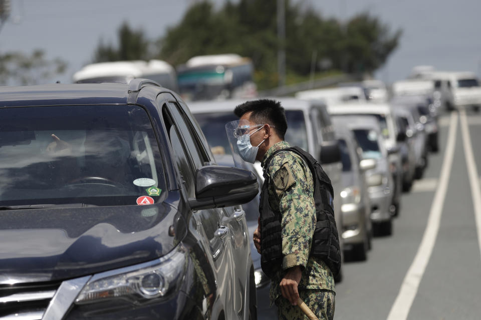 A policeman wearing protective gears inspects a driver at a checkpoint as the government implements stricter measures to prevent the spread of the coronavirus in Cavite province, Philippines on Monday, March 22, 2021. The Department of Health reported over 8,000 new COVID-19 cases Monday, the highest number since the pandemic hit the country last year as it struggles to contain an alarming surge in coronavirus infections. (AP Photo/Aaron Favila)