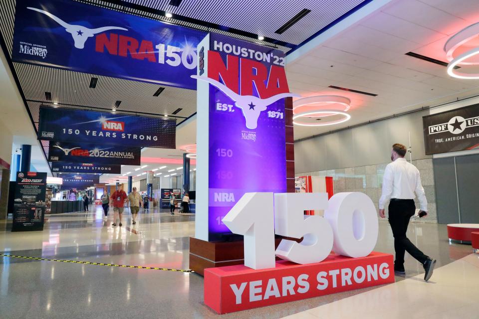 People walk past signage in the hallways outside of the exhibit halls at the NRA Annual Meeting held at the George R. Brown Convention Center Thursday, May 26, 2022, in Houston. (AP Photo/Michael Wyke)