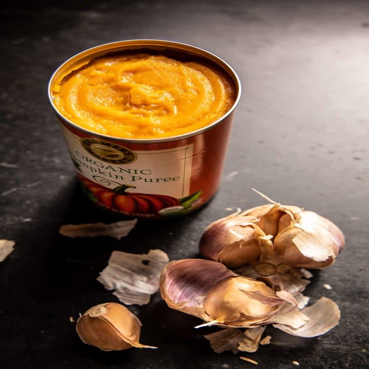 a can of pumpkin puree and several garlic cloves on a counter