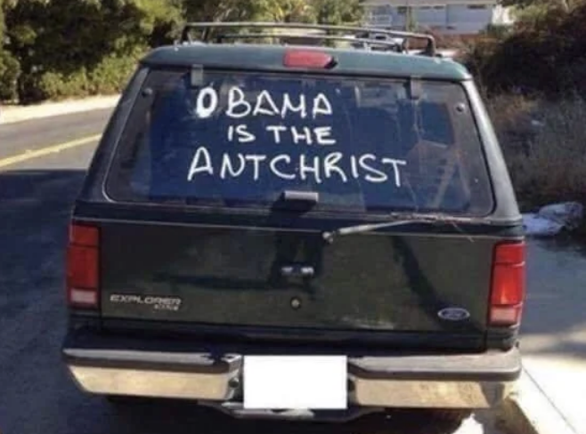 Rear window of a car with text "OBAMA IS THE ANTCHRIST" written on it