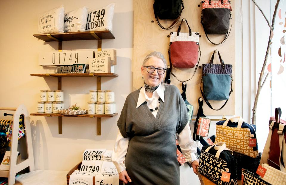 Sarah Bertochi poses in front of some handmade bags she created and is selling at her new store, Sarah Bertochi-Handmade at 63A Main St. in downtown Hudson, March 23, 2023.