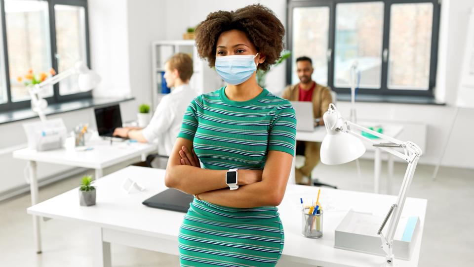 Woman with smart watch in medical mask at office stock photo