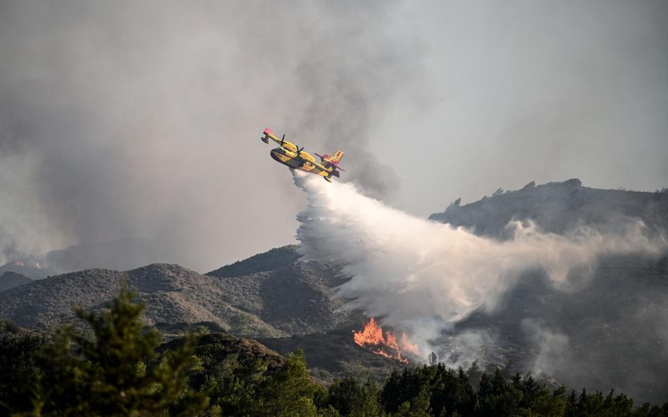 A firefighting plane drops water on a forest fire near the village of Vati on the southern part of the Greek island of Rhodes