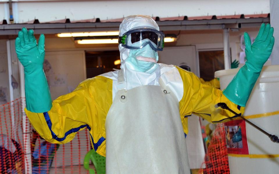 A health worker wearing protective gear is sprayed with disinfectant at the Nongo ebola treatment centre in Conakry, Guinea - AFP/AFP