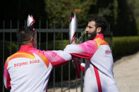 The first torch bearer, Greek alpine ski racer Ioannis Antoniou, right, greets the second bearer, former Chinese speed skater Li Jiajun, before passing the flame to him, after the lighting of the Olympic flame at Ancient Olympia site, birthplace of the ancient Olympics in southwestern Greece, Monday, Oct. 18, 2021. The flame will be transported by torch relay to Beijing, China, which will host the Feb. 4-20, 2022 Winter Olympics. (AP Photo/Thanassis Stavrakis)