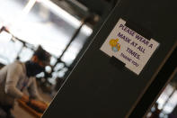 A sign encouraging the use of face coverings at all times is taped to a beam along the main concourse of an empty Coors Field before the Colorado Rockies host the San Diego Padres in a baseball game Sunday, Aug. 2, 2020, in Denver. (AP Photo/David Zalubowski)