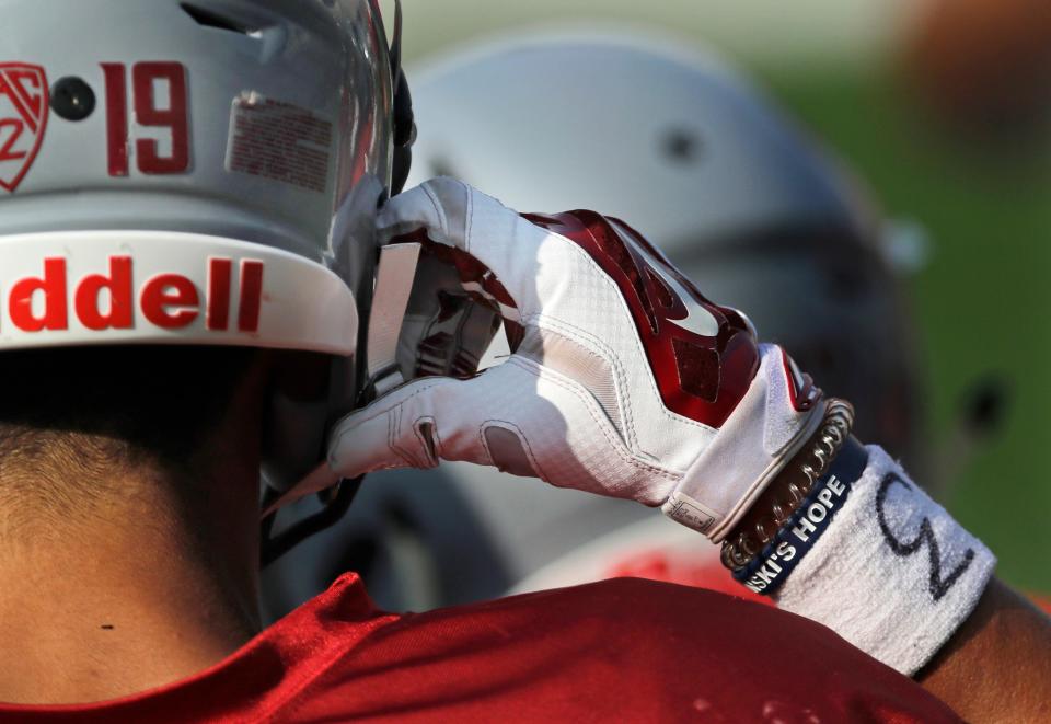 In this photo taken Aug. 16, 2018, Washington State wide receiver Brandon Arconado puts on his helmet while wearing a sweatband with a #3 on it in tribute to former WSU quarterback Tyler Hilinski during NCAA football practice in Pullman, Wash. Hilinski was expected to be the Cougars' starting quarterback for 2018, but he took his life on Jan. 16, 2018, at the age of 21. (AP Photo/Ted S. Warren)