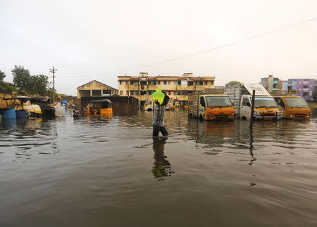 A man carries drinking water in a pitcher through a flooded street in Chennai, India, December 4, 2015. REUTERS/Anindito Mukherjee