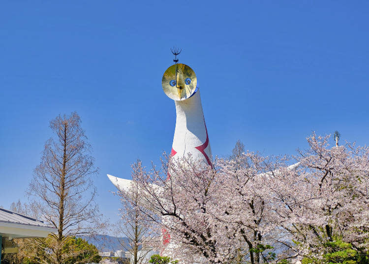 Tower of the Sun, designed with three faces on the outside and a fourth inside, and cherry blossoms